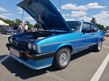 Offene Motorhauben mit gepflegtem Motorraum locken Zuschauer an
Open bonnets with well-maintained engine compartments attract spectators
Les capots ouverts avec un compartiment moteur bien entretenu attirent les spectateurs